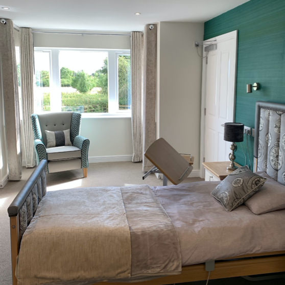 This bedroom at Mockley Manor Care Home in Warwickshire features luxury furnishings including cushions, throws, lighting and a beautifully upholstered profile bed.